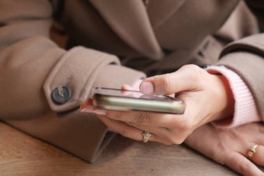 Bir kişi bir kafede akıllı telefon kullanırken bir masada oturur..