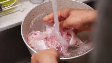 Eller lavaboda akan suyun altında çiğ tavuk yıkar. Yemek hazırlığı.