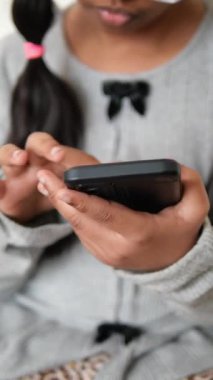 Küçük kız kapalı bir ortamda akıllı telefon kullanıyor..