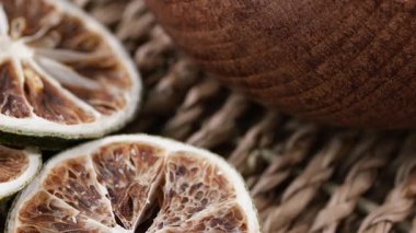 Kurutulmuş narenciye dilimleri bir masanın üzerindeki ahşap kasenin yanına konur..