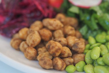 Nohut, salata sebzeleri ve dilimlenmiş sebzeler bir tabağa konur..