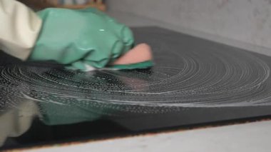 Bir insan elektrikli ocağı sabun ve bezle temizliyor..