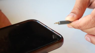 Birisi evdeki akıllı telefona şarj kablosu bağlıyor..
