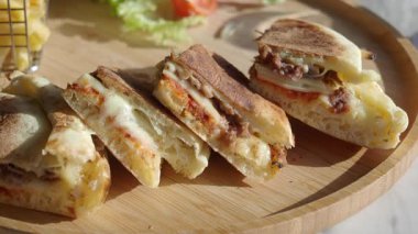 İnsanlar kalabalık bir kafede ekmek ve peynirle yapılan sandviçleri yiyorlar..