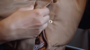 Bir insan basit adımlarla cekete nasıl düğme dikileceğini gösterir..