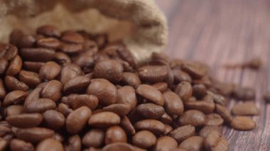 Kahve çekirdekleri, ahşap bir masanın üstündeki çuval bezinden dökülüyor..
