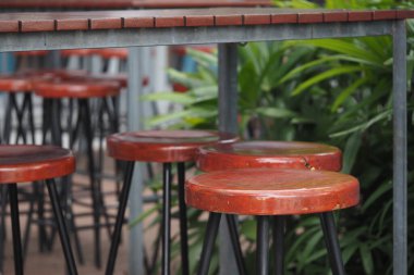 Binanın dışındaki yeşil santrallerin yanında birkaç tahta bar taburesi var..