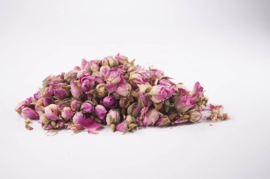 Kurumuş pembe gül tomurcukları düz beyaz bir yüzeyde dinleniyor. Küçük ve renkliler..