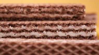 Çikolatalı gofret tabakaları düzgünce dizilmiş ve sarı bir arka planı var..