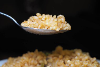 Sıcak bir kase pişmiş bulguru kaşıkta servis edilir..