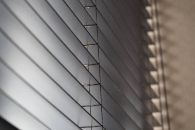 Gündüz vakti bir odada ışık yatay perdelerin arasından parlar..