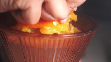 Bir el portakalı sıkıyor ve bardağa meyve suyu sıkıyor..