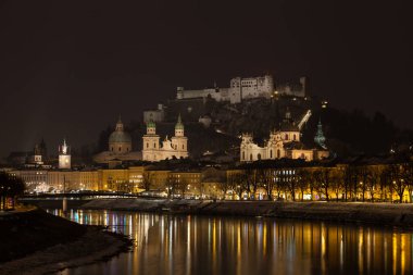 Salzburg, Avusturya 'da Salzach Nehri' nin karşısında gece görüşü. Arka planda Hohensalzburg Kalesi var..