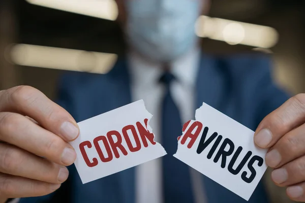 Close up of man's hands tearing paper with word coronavirus , selective focus. Stop virus concept