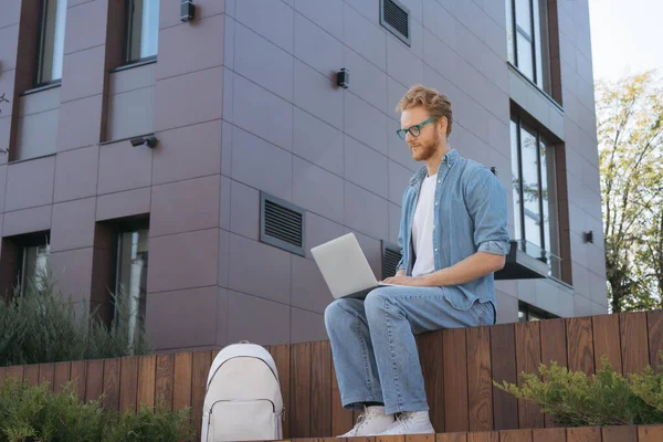 Student studying, exam preparation, distance learning, online education concept. Handsome red haired man copywriter using laptop computer, typing, working freelance project sitting at workplace