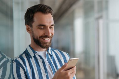 Cep telefonu kullanan, internetten iletişim kuran yakışıklı bir iş adamı. Mutlu sakallı adam rezervasyon yaptırıyor.