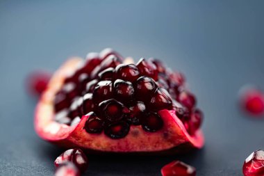 Siyah arka planda taze, olgun bir nar. Nar kesimi ve tohumları dağılmış. Makro fotoğrafçılık.