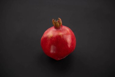 Siyah arka planda taze, olgun bir nar. Kırmızı bir meyvenin yakın çekimi