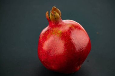 Siyah arka planda taze, olgun bir nar. Kırmızı bir meyvenin yakın çekimi