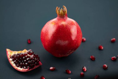 Siyah arka planda taze, olgun bir nar. Nar kesimi ve tohumları dağılmış. Makro fotoğrafçılık
