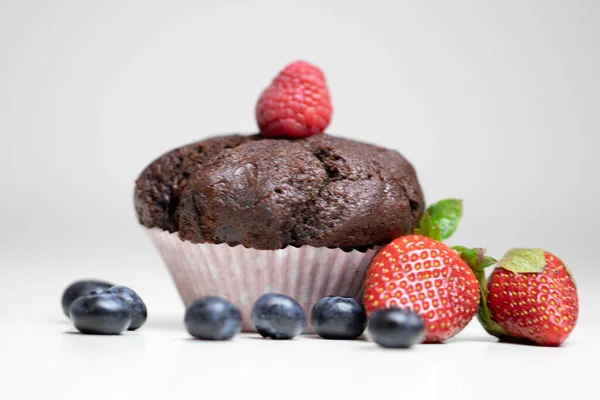 Baked chocolate muffin with juicy berries, strawberries, blueberries, raspberries. Stock Image