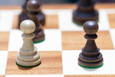 Satranç tahtasında tahta satranç oynamak. Taktik ve strateji. Siyah ve beyaz şekiller