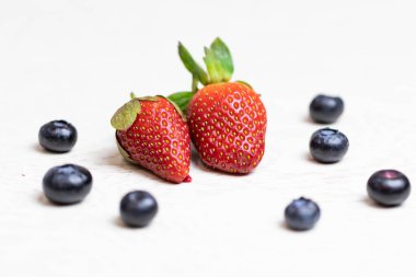 Beyaz arka planda olgun ve sulu çilekler ve yaban mersinleri. Sağlıklı beslenme