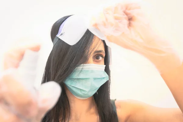 Close up macro disinfectant spray in woman hands with caucasian woman with face mask in the background. Disinfection concept.