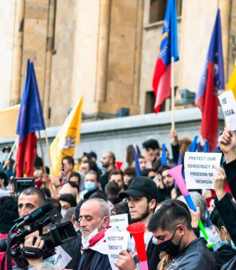 1 Kasım, 2020. Tiblis. Gürcistan Cumhuriyeti. Seçim sonrası protesto sırasında parlamento binasının önünde posterleri ve bayrakları olan kalabalık.
