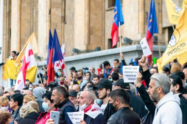 1 Kasım, 2020. Tiblis. Gürcistan Cumhuriyeti. Seçim sonrası protesto sırasında parlamento binasının önünde posterleri ve bayrakları olan kalabalık.