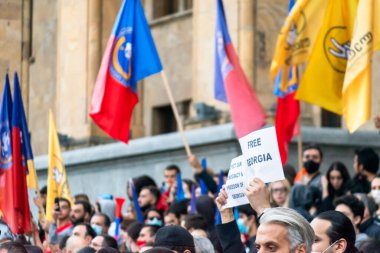 1 Kasım, 2020. Tiblis. Gürcistan Cumhuriyeti. Seçim sonrası protesto sırasında parlamento binasının önünde posterleri ve bayrakları olan kalabalık.