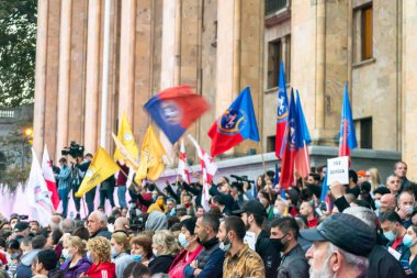1 Kasım, 2020. Tiblis. Gürcistan Cumhuriyeti. Seçim sonrası protesto sırasında parlamento binasının önünde posterleri ve bayrakları olan kalabalık.