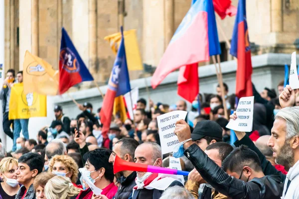 1 Kasım, 2020. Tiblis. Gürcistan Cumhuriyeti. Seçim sonrası protesto sırasında parlamento binasının önünde posterleri ve bayrakları olan kalabalık.