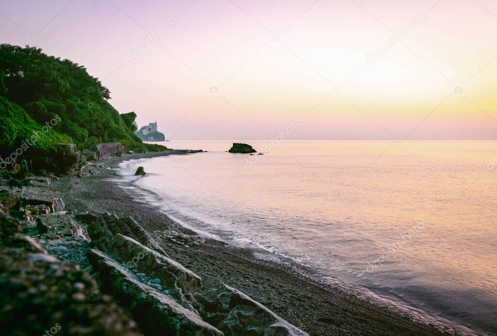 Rocky Tsikhisdziri beach landscape with calm sea during blue hour and green nature and rocky ruins blocks nearby. Georgia travelous and scenic places concept.