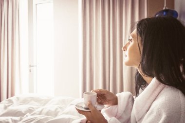 Beyaz kadın rahat bir yatakta sabah espresso içiyor. Boş alan arkaplan resmi.