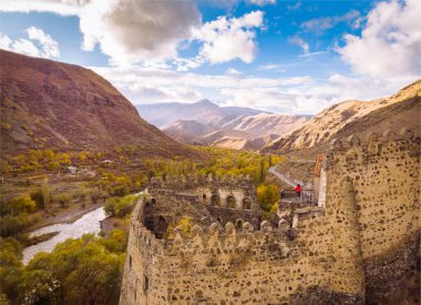 Kırmızı ceketli kız Khertvisi Kalesi 'ne bakıyor ve kafkas dağlarının büyüleyici manzarasına bakıyor. Georgia 'da göz kamaştırıcı yerler. Kafkasya 'da seyahat.