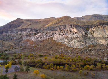 Vardzia mağara şehrinin yukarıdan havadan bakış açısı. Paravani nehri ve sonbahar doğası ön planda. Tarihsel unesko alanları Georgia.