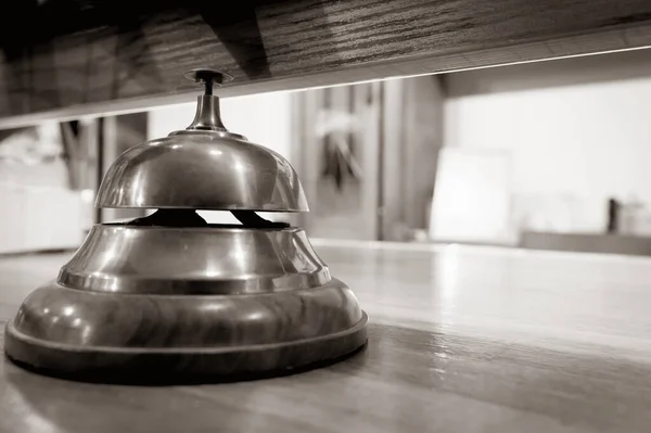 Giant ring bell on the wooden front desk with nobody around.Notice message nonverbal concept.