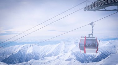 28 Şubat 'ta. Gudaur.Georgia White Ski kaldırma kabini kayakçıların siluetleri ve karlı kafkas dağlarının arka planlarıyla