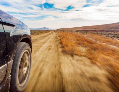 4x4 'lük araç tekerleklerini yakın plan terkedilmiş arka plan ile yolda hareket halinde.
