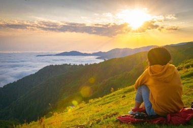 Dişi kişi oturur ve Gomismta 'daki bulutların üzerindeki büyüleyici manzaranın tadını çıkarır. Gürcistan gezisi