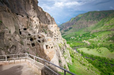 Arkaplanda yeşil kanyon bulunan VArdzia şehir mağaralarının panoramik bakış açısı