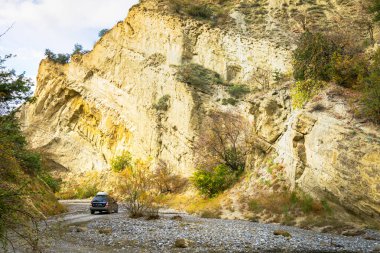 Koyu 4WD araba, sonbahar doğasıyla çevrili kayalık bir vadide izole edilmiş. VAshlovani Milli Parkı.