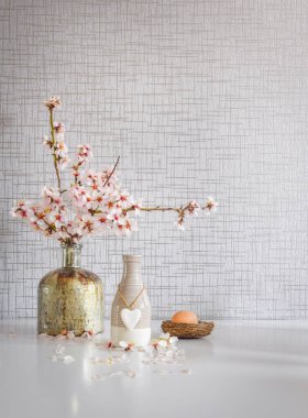 Buket tarzı beyaz mutfak masası sarı ile kurulmuş yeşil, kırmızı bardaklar, vazoda çiçek açan papatya çiçekleri ve paskalya yumurtası.