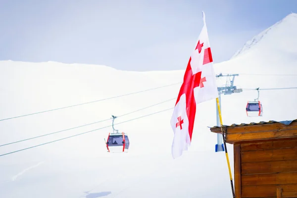Georgian flag with Gudauri panorama and ski cabin lifts and snowy mountain background.Ski holiday destination Georgia