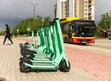 Siauliai, Litvanya - 29 Mayıs 2021: Gren bol elektrikli scooter otobüs ve Gil arka planda yürüyor. Litvanya ve Baltık 'ta ulaşım türleri.