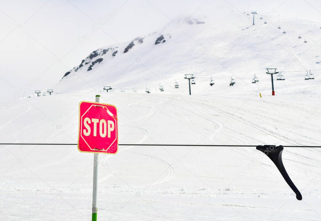 Red Stop post sign i ski resort with mountains panorama. Ski holiday safety and dangerous slopes concept.