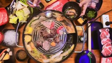 Geleneksel Tayland BBBQ bifteği (Moo Krata), karışık deniz ürünleri, ahtapot, karides, balık köftesi, erişte, mantar, lahana, mısır, sarımsak ve Tayland, Bangkok 'ta ahşap masaya soslar..