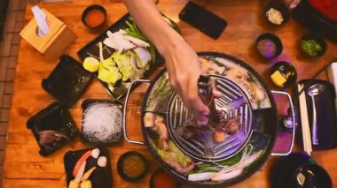 Geleneksel Tayland BBBQ bifteği (Moo Krata), karışık deniz ürünleri, ahtapot, karides, balık köftesi, erişte, mantar, lahana, mısır, sarımsak ve Tayland, Bangkok 'ta ahşap masaya soslar..