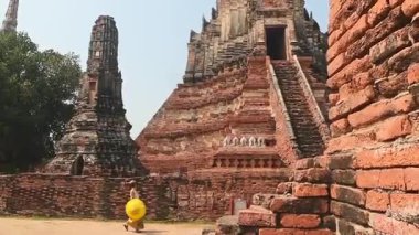 Tayland, Ayutthaya - 15 Mart 2023: Geleneksel Tayland elbisesi giyen kadın antik Buda heykelini ziyaret ediyor. Ayutthaya tarihi parkı. UNESCO Dünya Mirası Alanı